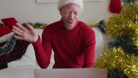 hombre afroamericano albino feliz con sombrero de papá noel haciendo una videollamada en navidad