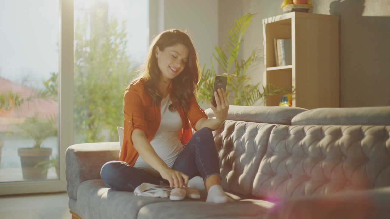 Pregnant Woman Taking Selfie with Baby Clothes