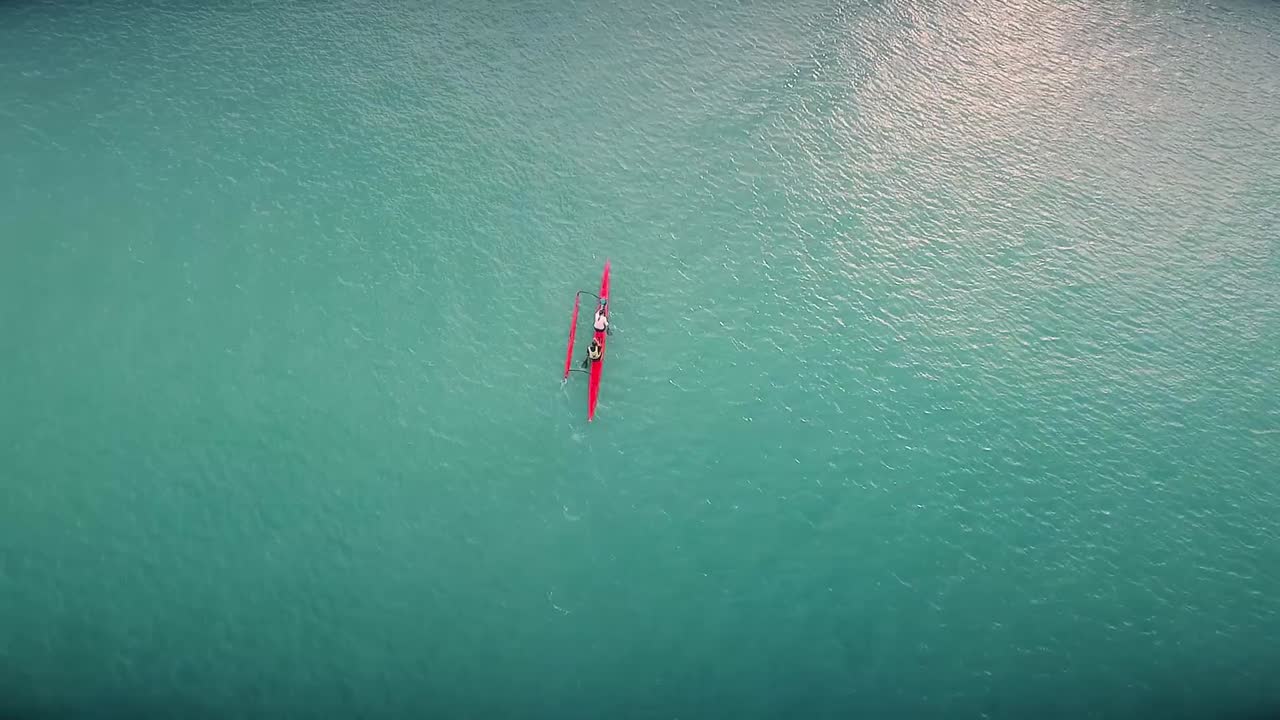 drone video de un kayak deportivo remando a través de un gran lago hacia un gran barco en un hermoso y caluroso día en tailandia