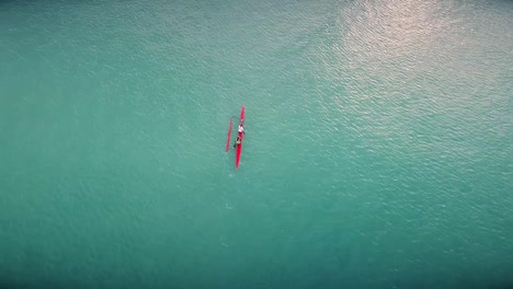 drone video de un kayak deportivo remando a través de un gran lago hacia un gran barco en un hermoso y caluroso día en tailandia