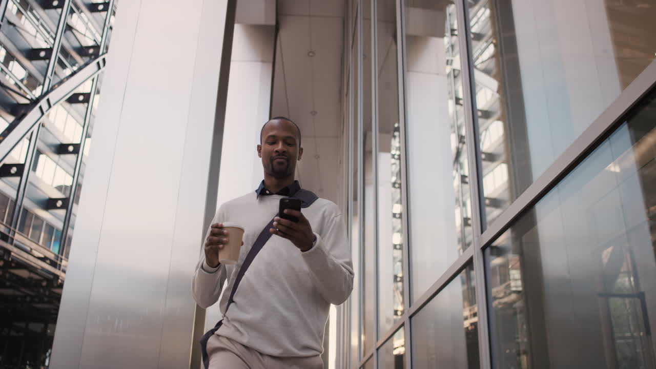 Empresário afro-americano caminhando pela cidade usando smartphone