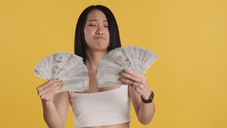 asian woman looking happy while holding money on camera.