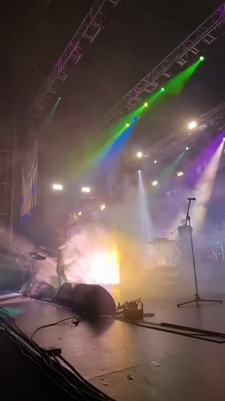 Rekaman video sudut rendah panggung konser yang semarak dengan lampu warna-warni dan efek kabut.