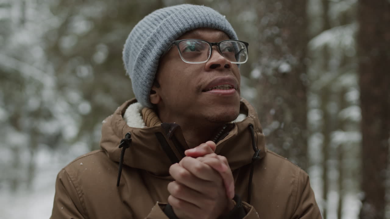 человек, согревающий руки в снежном лесу.