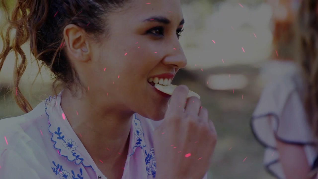 Vertical video: Reaching for cracker, woman in pink blouse and friend sharing snacks at park picnic