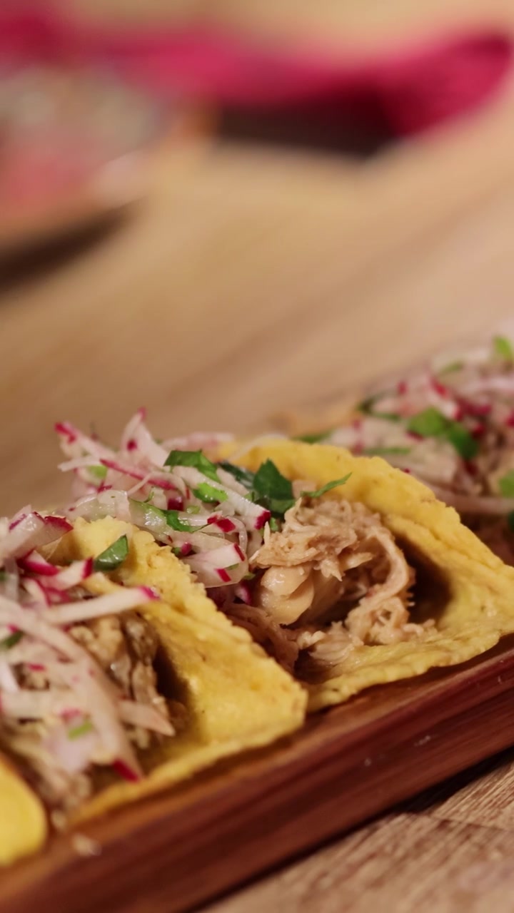 Primo piano di tacos gourmet su un tavolo di legno in un ristorante di Bangkok illuminato calorosamente, che evidenzia ingredienti vivaci e un'atmosfera invitante