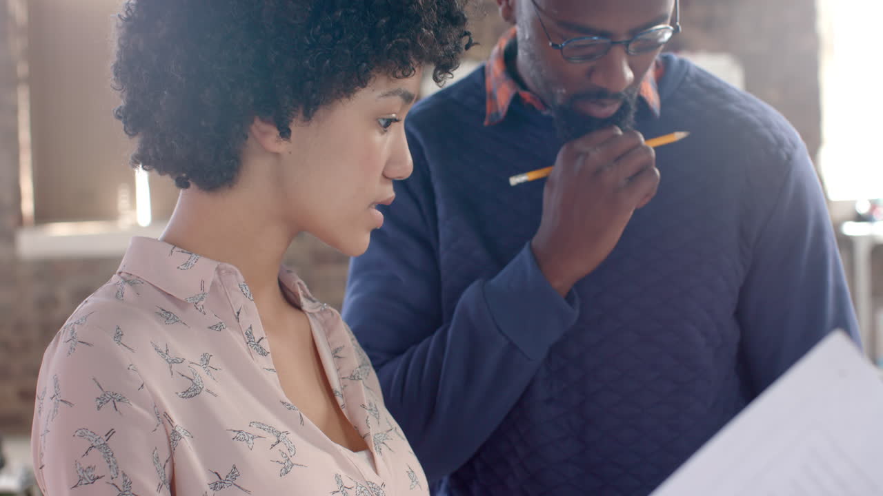Young African American man and woman review business documents in an office setting