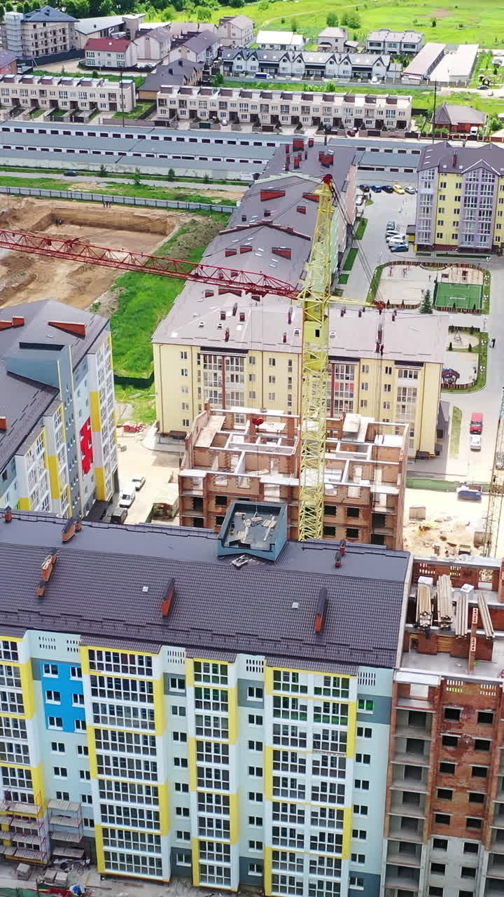Modern construction area in the city. New residential complex is building in summer. Tower crane in a construction site. Vertical video