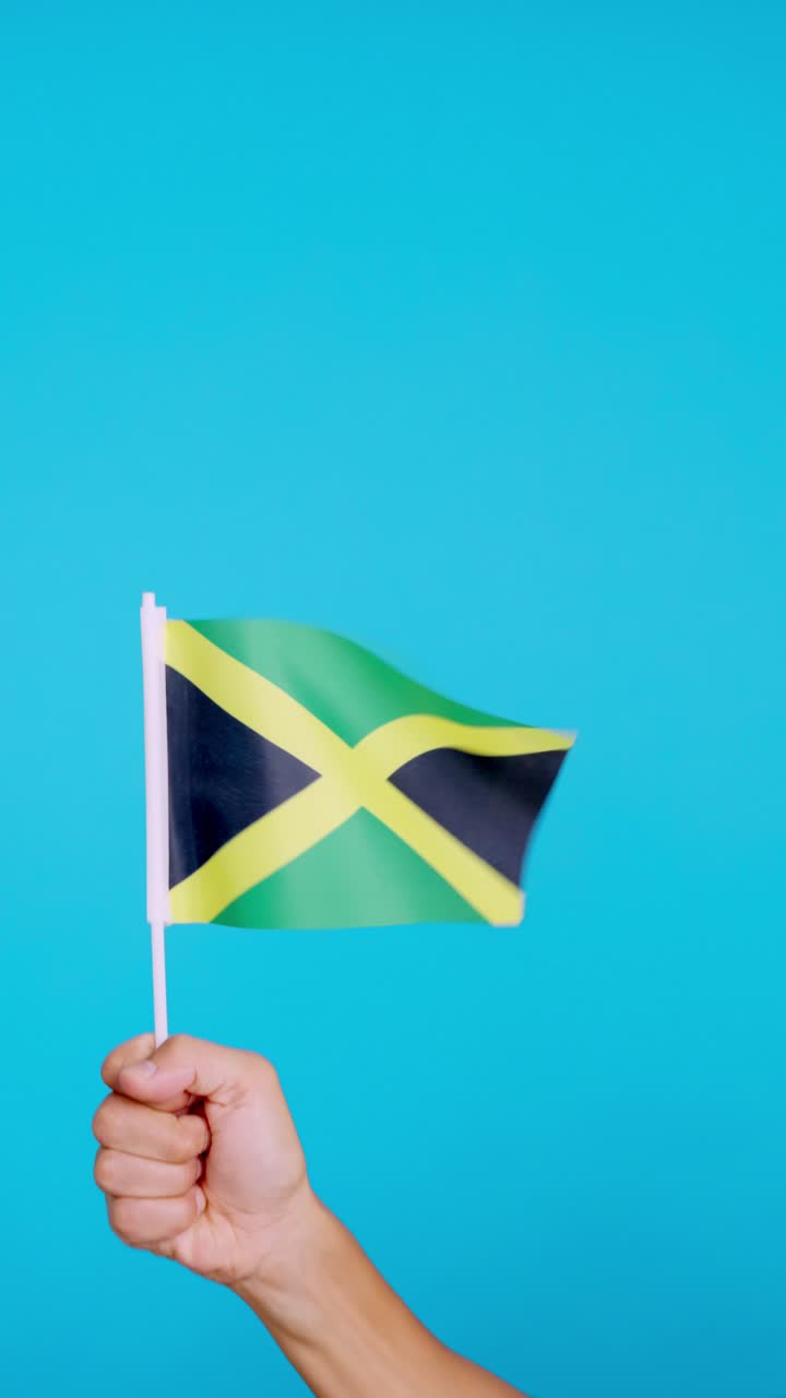 Hand lifting a jamaican pennant while waving by the wind