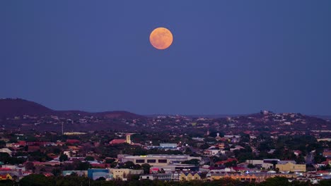 Recorra-La-Ciudad-De-Willemstad-Curacao-Al-Anochecer-Mientras-Una-Rara-Superluna-Azul-Llena-Se-Eleva-En-Rojo-Contra-El-Cielo-Púrpura