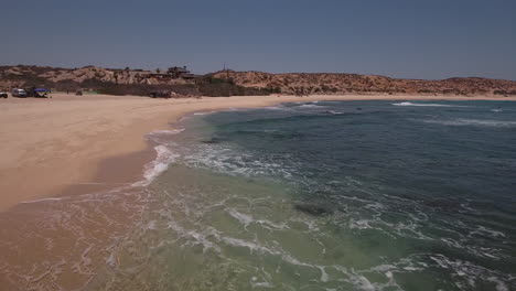 Low-Flying-Drone-over-ocean-waters-at-rocky-beach-at-Cabo-San-Lucas,-Mexico