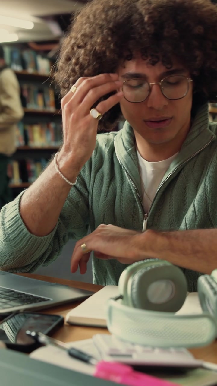 Studentessa esausta che riposa la testa sulla scrivania in biblioteca