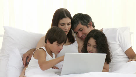 Padres-E-Hijos-Usando-Una-Computadora-Portátil-En-La-Cama