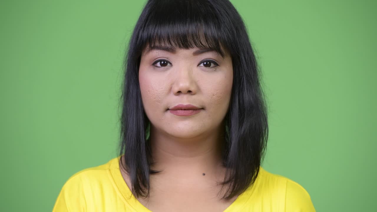 Beautiful happy Asian woman smiling against green background