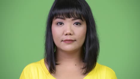 beautiful happy asian woman smiling against green background