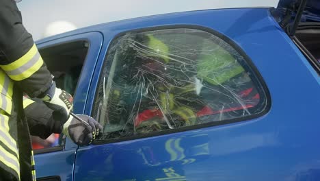 breaking side window during rescue operation of firefighters after a car accident in slow motion