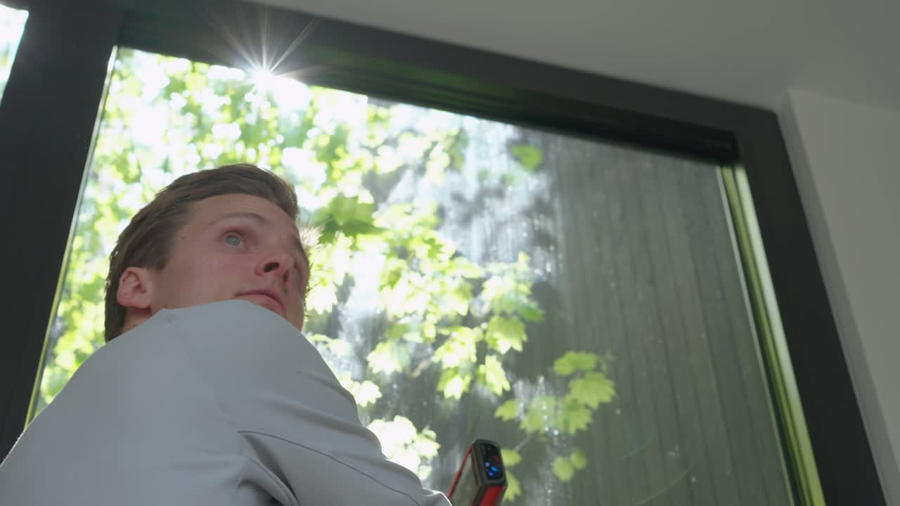 현대 가정의 창문 근처에서 측정하는 평면도 전문가의 와이드 샷