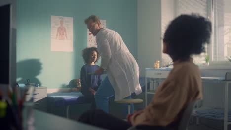 man doctor giving medical advice african mother after examining teen daughter.