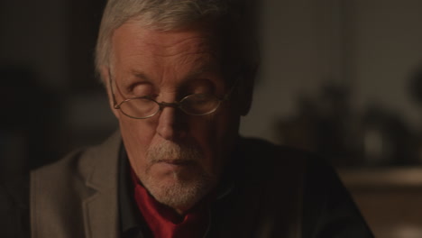 old passionate man writes a letter in his office at night