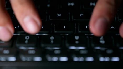 close up footage of young businessman hands busy working, searching and studying by typing on glowing keyboard in the dark for send emails and surf on a web browser, revert shot