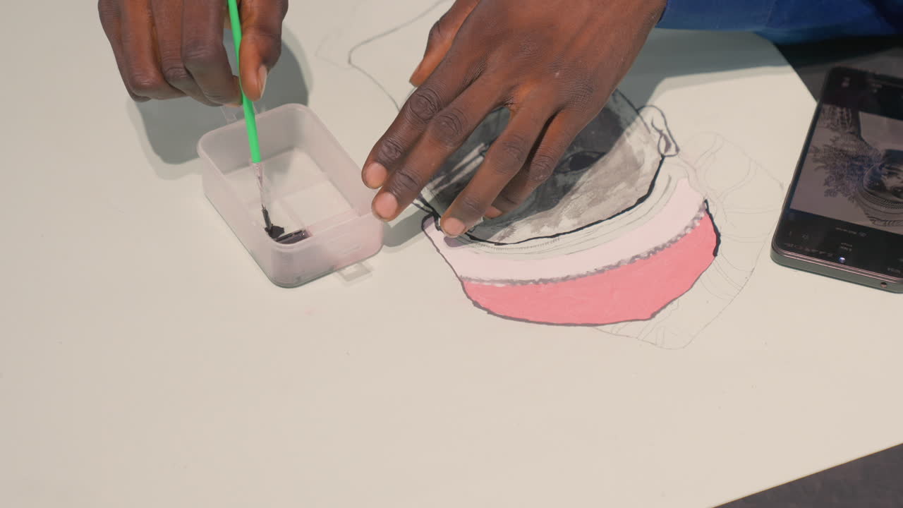 Detail of black artist mixing ink for painting restoration, dipping brush into small container, precise pigment blending, steady hands touching up grayscale portrait with pink cap, careful cleanup