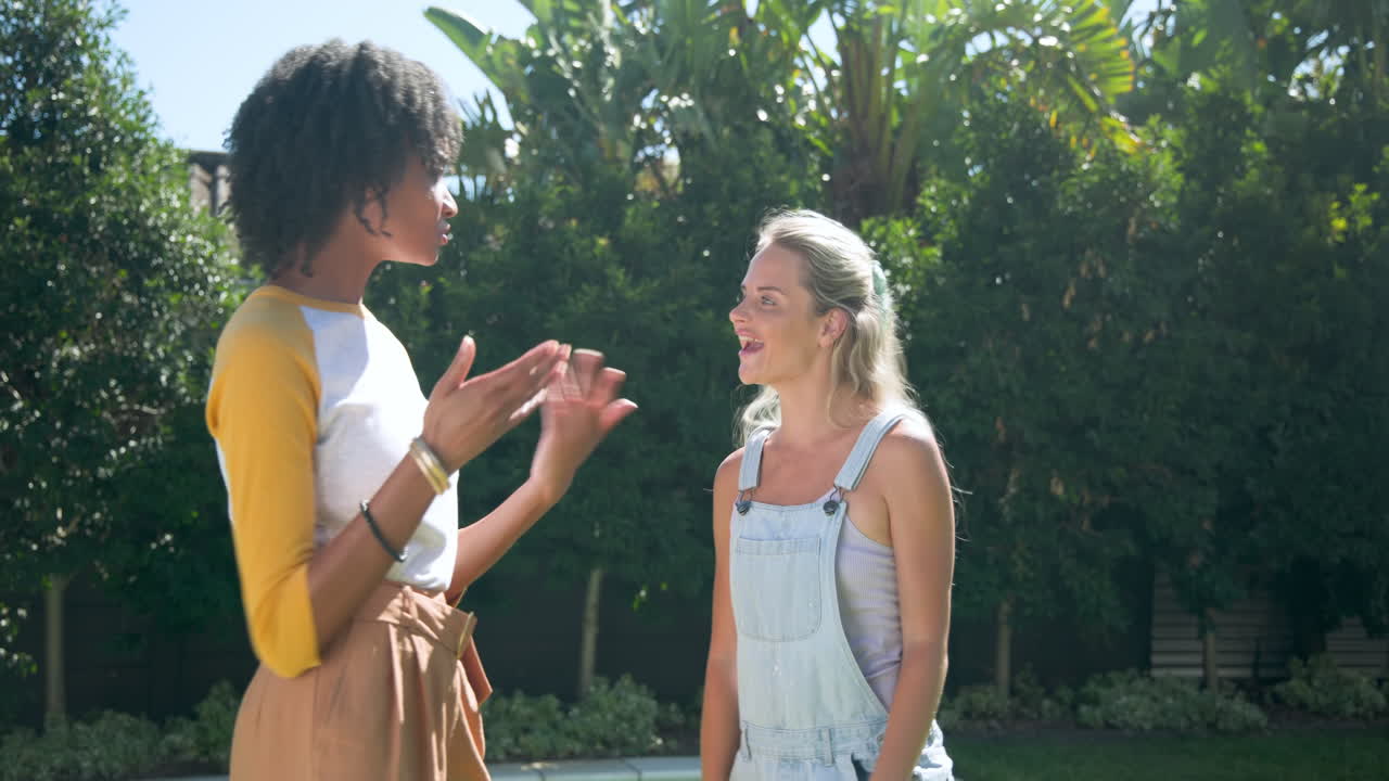 African American woman and friend talking and laughing outdoors near pool