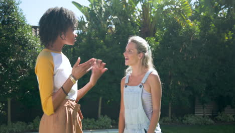 african american woman and friend talking and laughing outdoors near pool