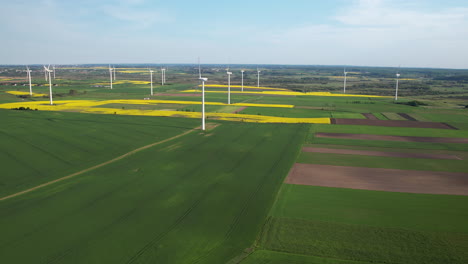 aerial view of wind turbine farm on agricultural green and yellow colored fields in nature - production of new energy