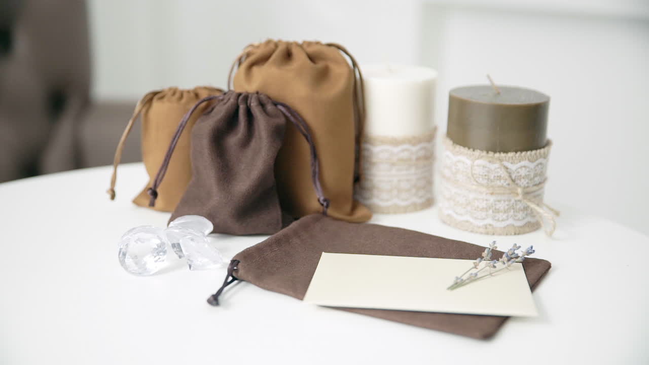 아름다운 여성 손이 촛불이 있는 밝은 흰색 테이블에 결혼식이나 휴가 초대장을 쓰고 있습니다.