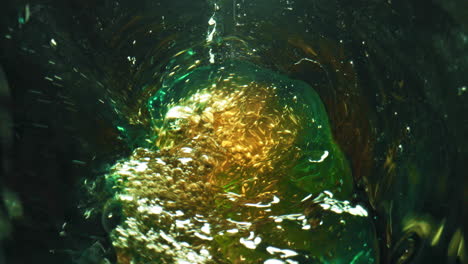 bottle swirling craft beer closeup. lager stream making foam in green glass