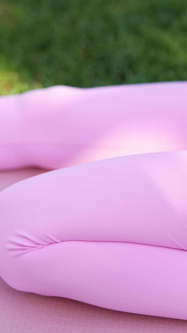 женщина сидит в розовых леггинсах, на открытом воздухе