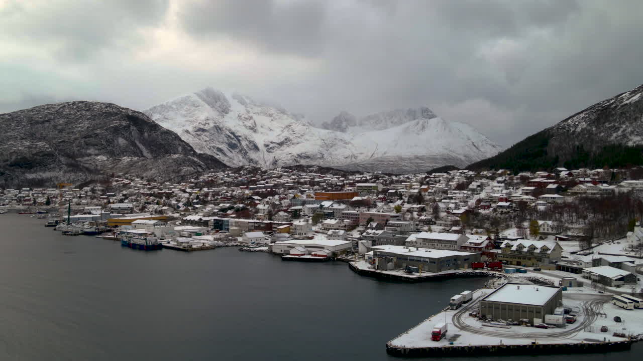 fiordo tranquilo y pueblo de pescadores en la isla de skjervoy en el norte de troms, noruega con montañas alpinas nevadas en el fondo en un espectacular día de invierno