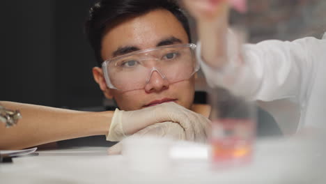 girl drips red paint into clear liquid during chemical test