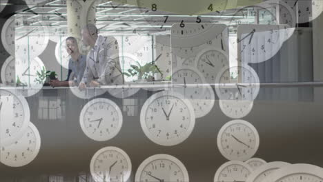 animation of moving clocks over diverse colleagues discussing work in office