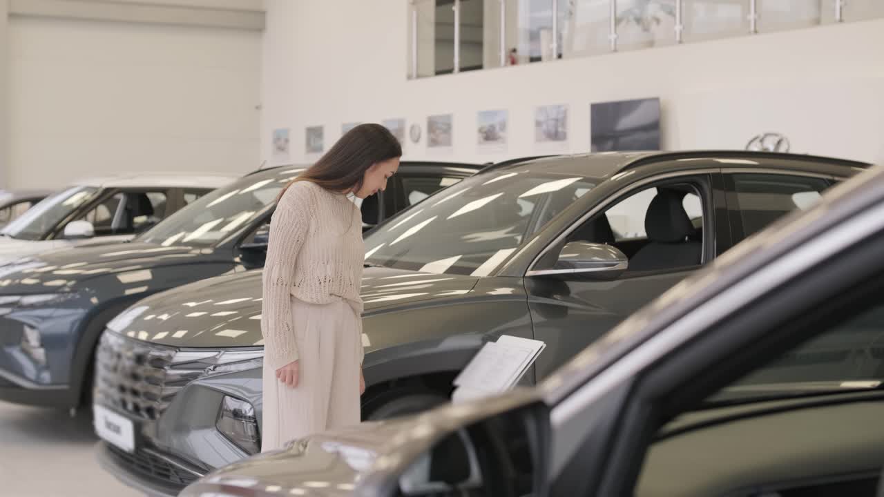 mujer eligiendo un coche en una sala de exposición de automóviles