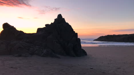 Devil's-Kitchen,-part-of-Bandon-Beach-State-Park-at-the-Southern-Oregon-coast-at-sunset,-people-sitting-on-rock