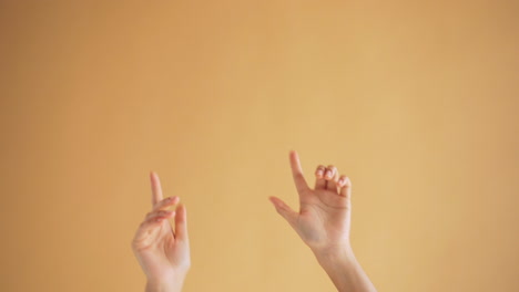 Hands in Motion against Light Orange Background