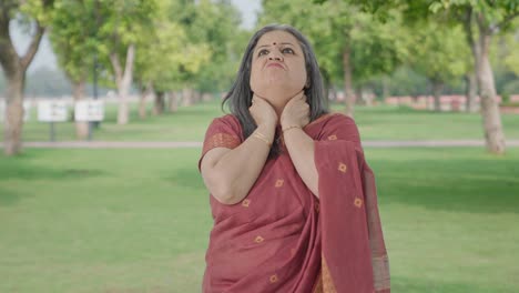 sick indian old woman suffering from neck pain in park