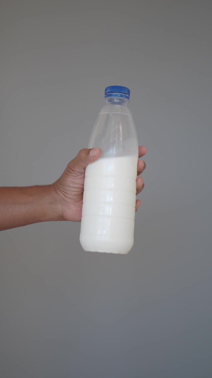 Mano sosteniendo una botella de plástico de leche fresca