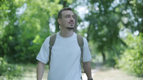 young man walking with guitar on street near forest