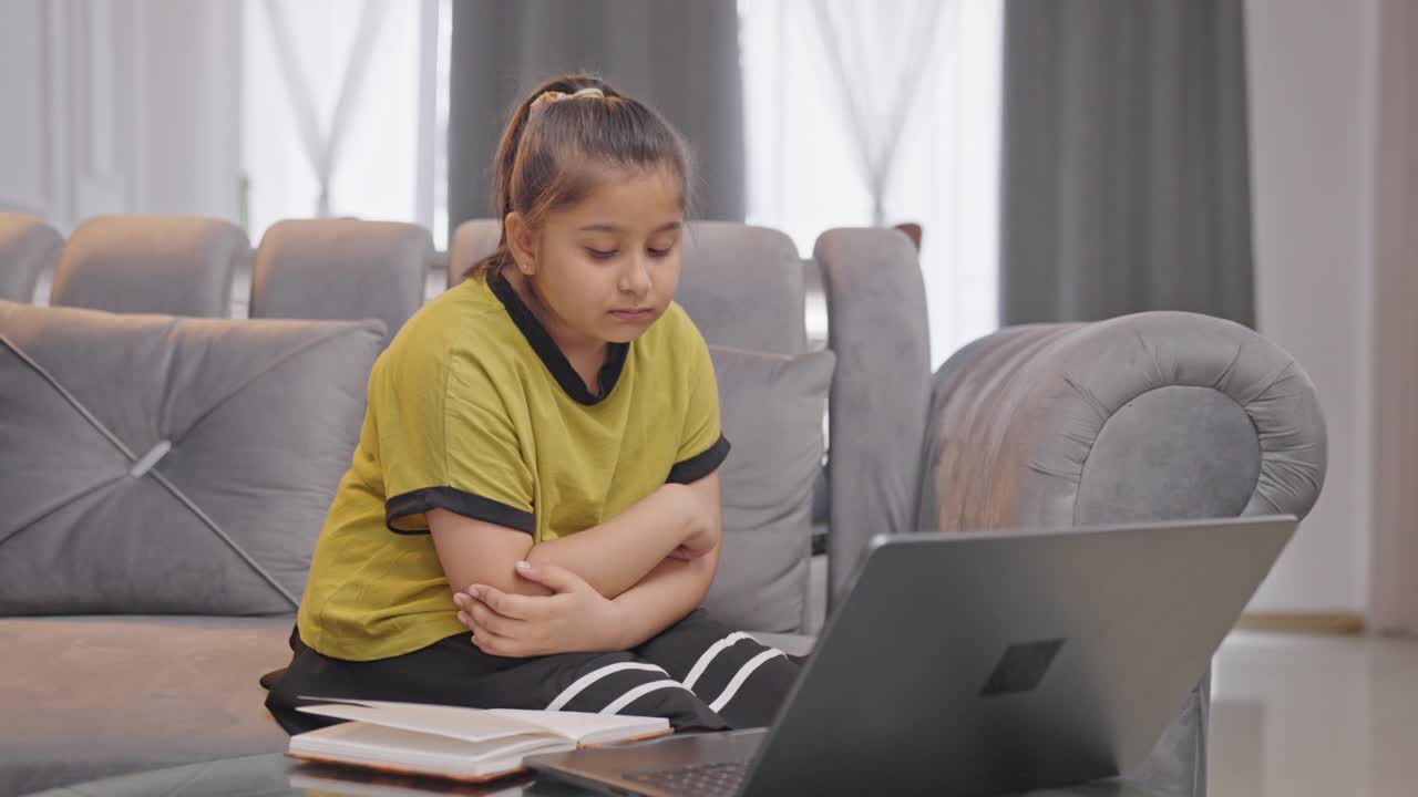 una niña india cansada usando una computadora portátil tratando de estudiar en línea