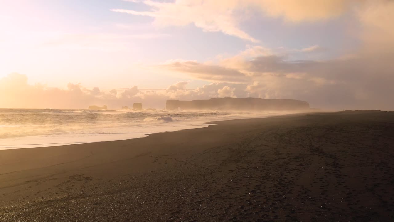 Indulge in the Captivating Aerial Footage of Iceland's Black Sand Beach, Featuring Powerful Waves Amidst the Sunset's Radiance
