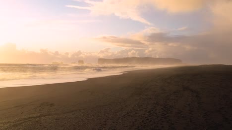 indulge in the captivating aerial footage of iceland's black sand beach, featuring powerful waves amidst the sunset's radiance