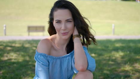 hermosa mujer modelo de moda con el pelo largo y castaño sentado en la hierba verde