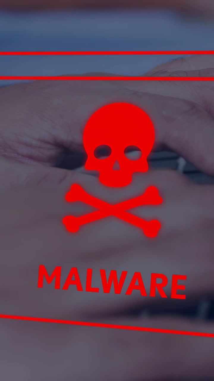 Vertical video: Man typing on laptop keys, red MALWARE warning appearing, glitching, obscuring keys