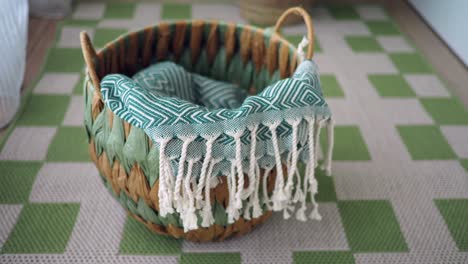 woven basket with green patterned blanket on checkered rug