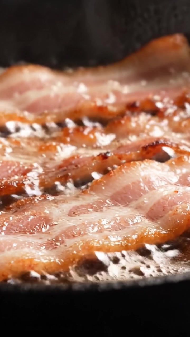 Sprød bacon, der steger: Fængslende nærbilleder af sprøde strimler, der steger på en varm pande, og viser den gyldenbrune tekstur og lækre aroma af denne morgenmadsfavorit.