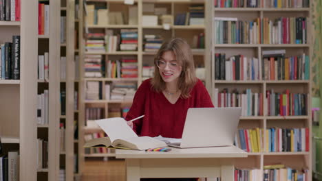 Estudiante-Caucásico-Con-Gafas-Investigando-En-La-Biblioteca-Usando-Una-Computadora-Portátil