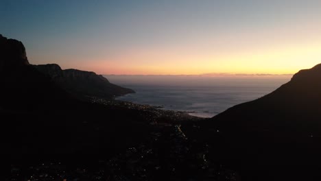 drone shot dolly over cape town south africa at sunset between the mountains with cars driving below