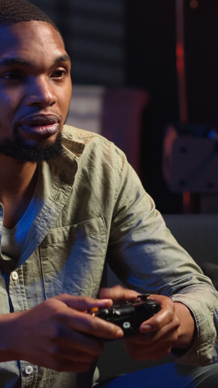 Vertical Video African american man spends free time playing video games with popcorn snack